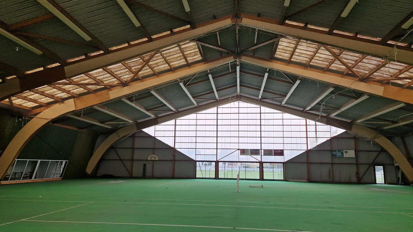 Court de tennis couvert, filet simple sous charpente bois